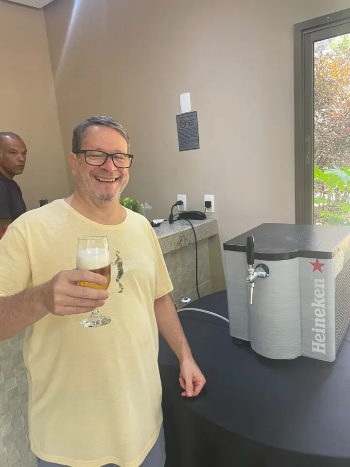 Participante brindando com chopp ao lado de chopeira Heineken da Senhor Chopeira